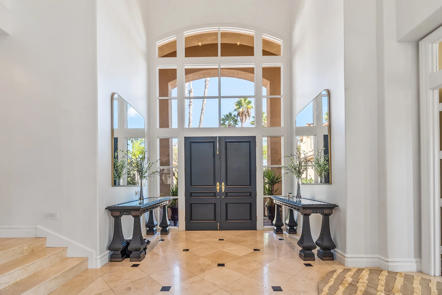 A bright entrance hall with dark double doors and tall arched windows.