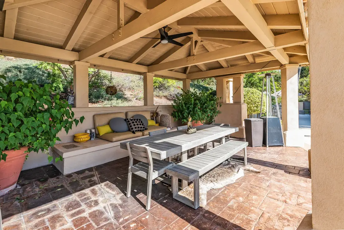 A covered patio with a dining table and built-in seating.