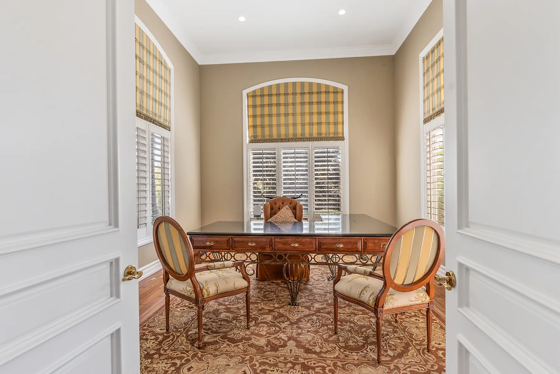 A formal sitting room with a glass-topped table and chairs on a patterned rug.