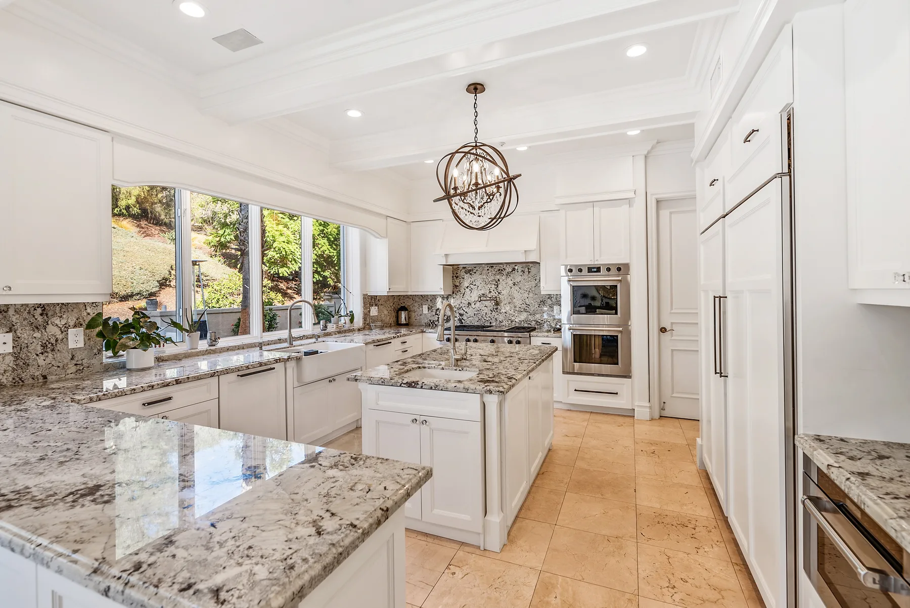 A bright kitchen with white cabinetry, stone countertops, and an island.