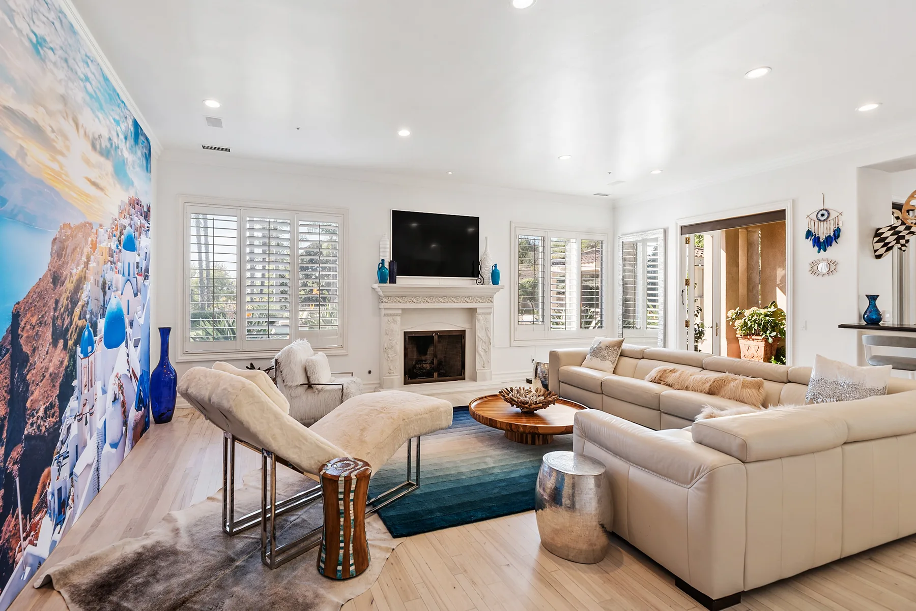 A bright living room with seating arranged around a fireplace and television.