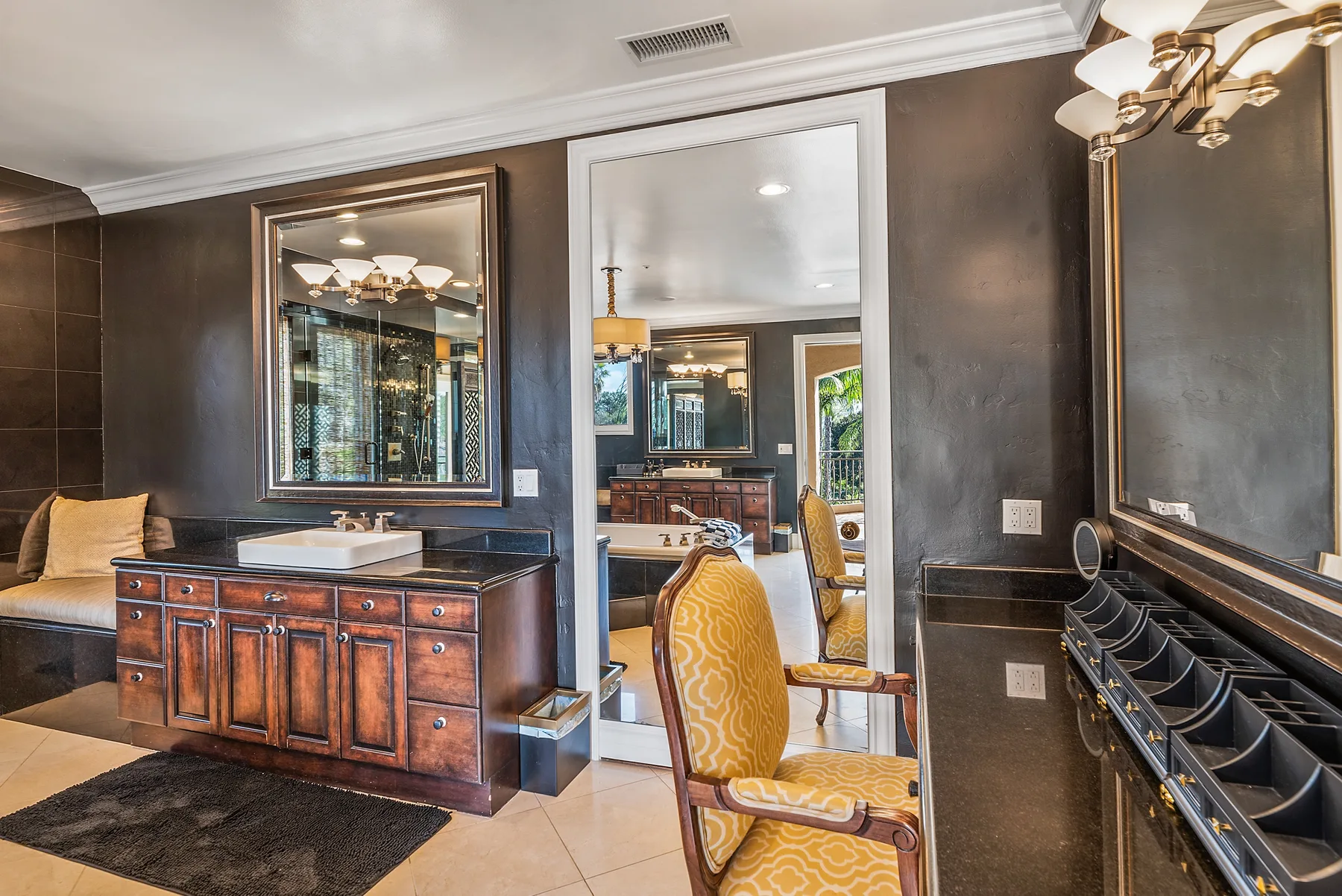 A bathroom vanity area with a large mirror and upholstered seating.