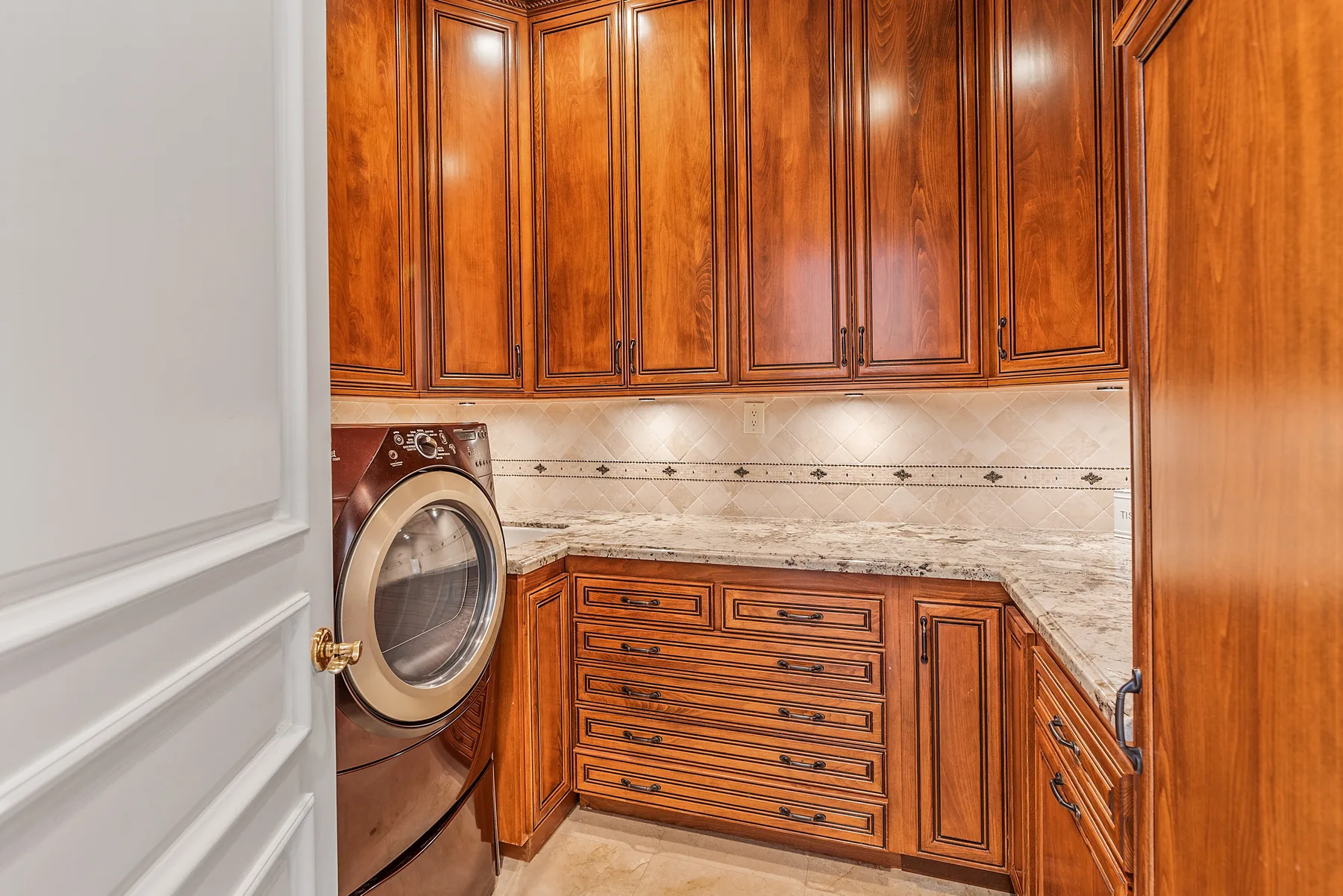 A laundry room with wooden cabinets and a front-loading washing machine.