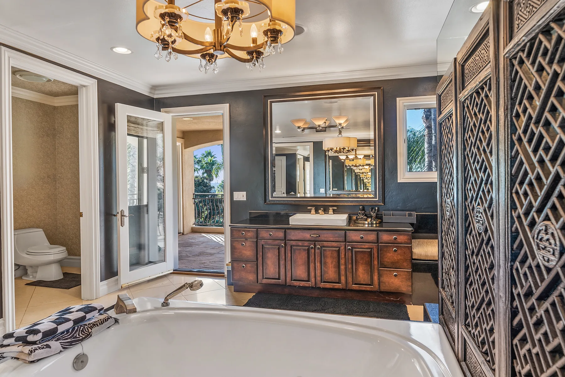 A bathroom with a large bathtub, dark vanity, and decorative patterned screen.