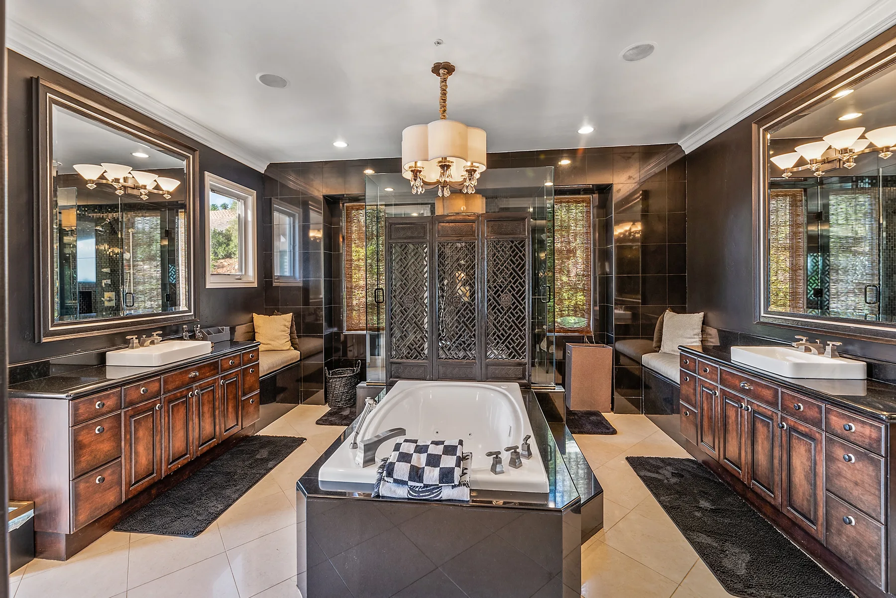 A spacious bathroom with a central bathtub, twin vanities, and dark cabinetry.