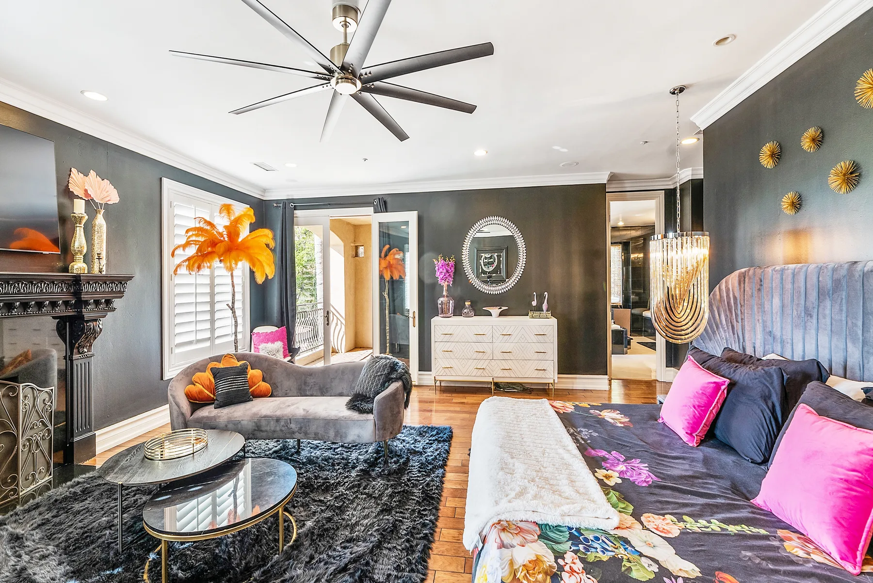 A decorated living room with seating, a fireplace, and a ceiling fan.