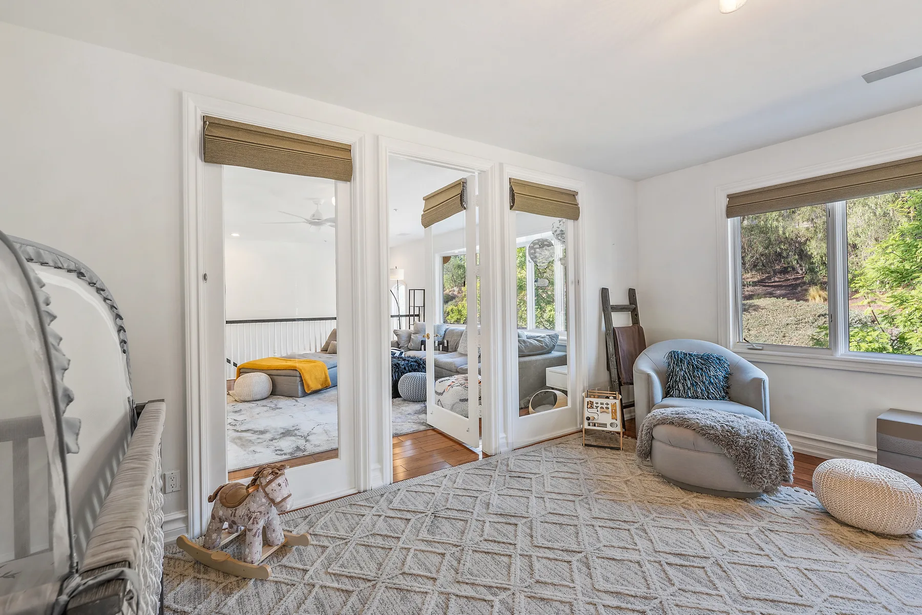 A bright sitting area with a large rug and a chair beside the windows.