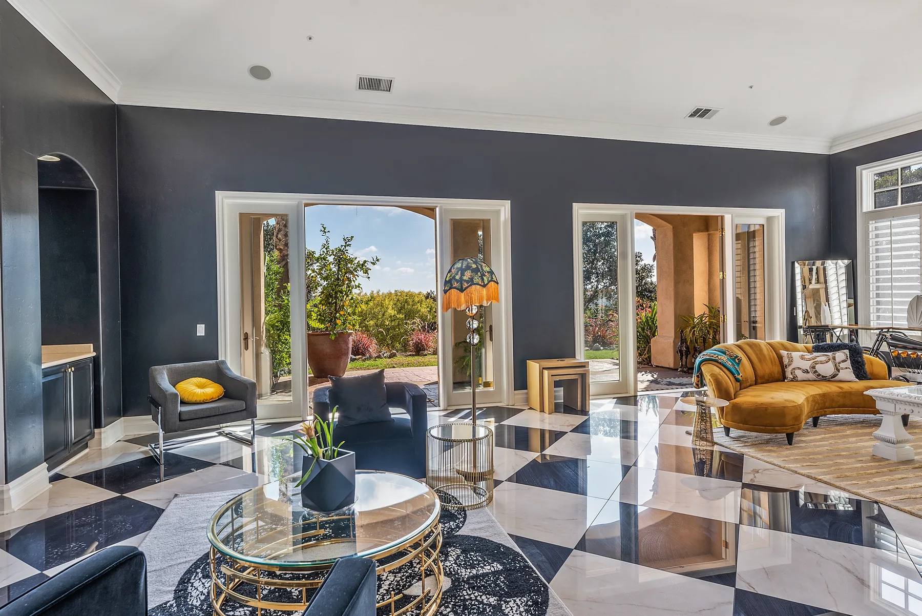 A bright living room with seating, a glass coffee table, and large windows.