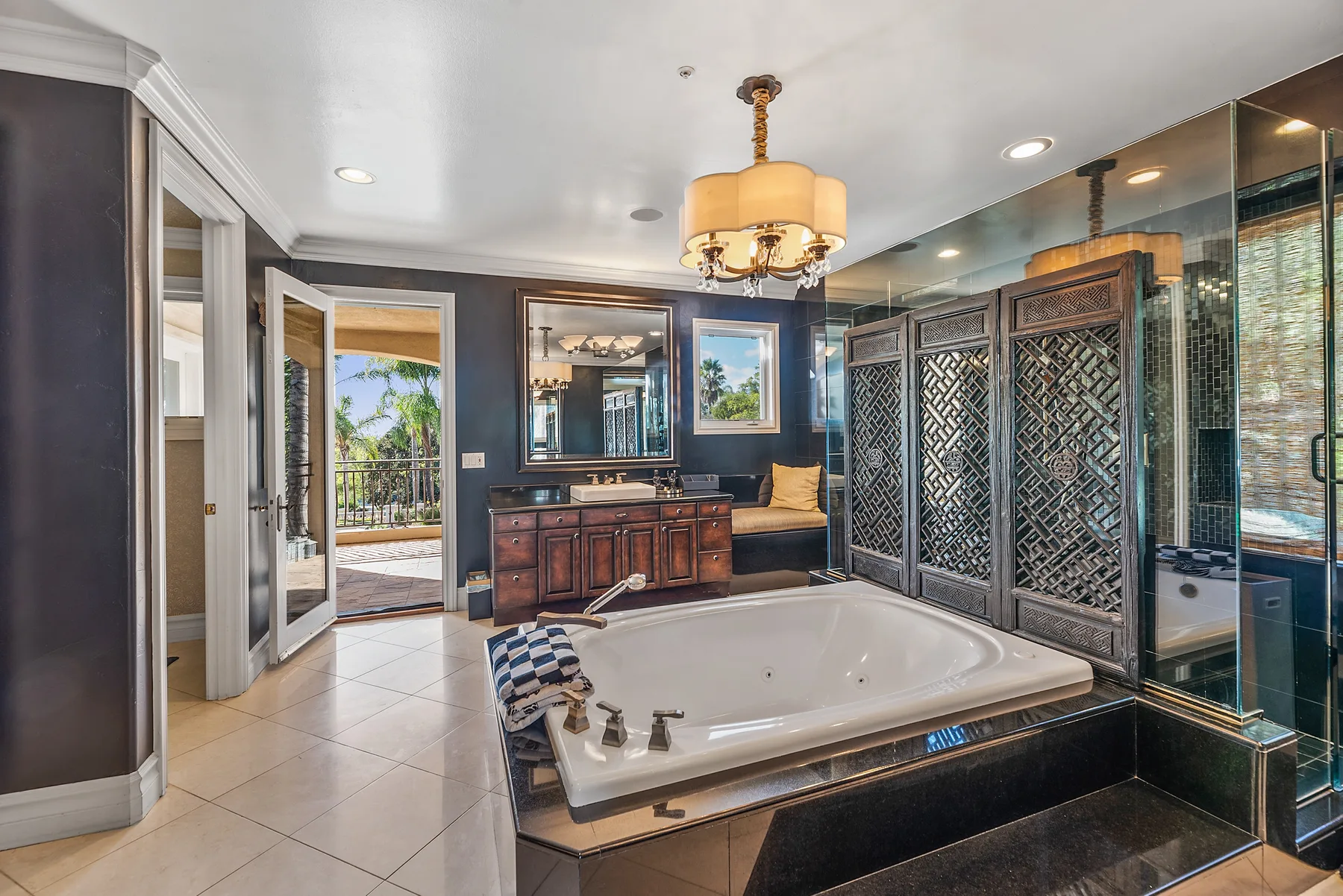 A spacious bathroom with a large bathtub and dark decorative screens.