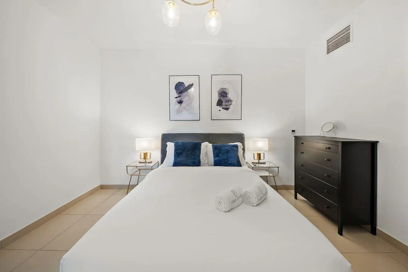 Un dormitorio luminoso con una cama bien tendida y mesitas de noche a juego.