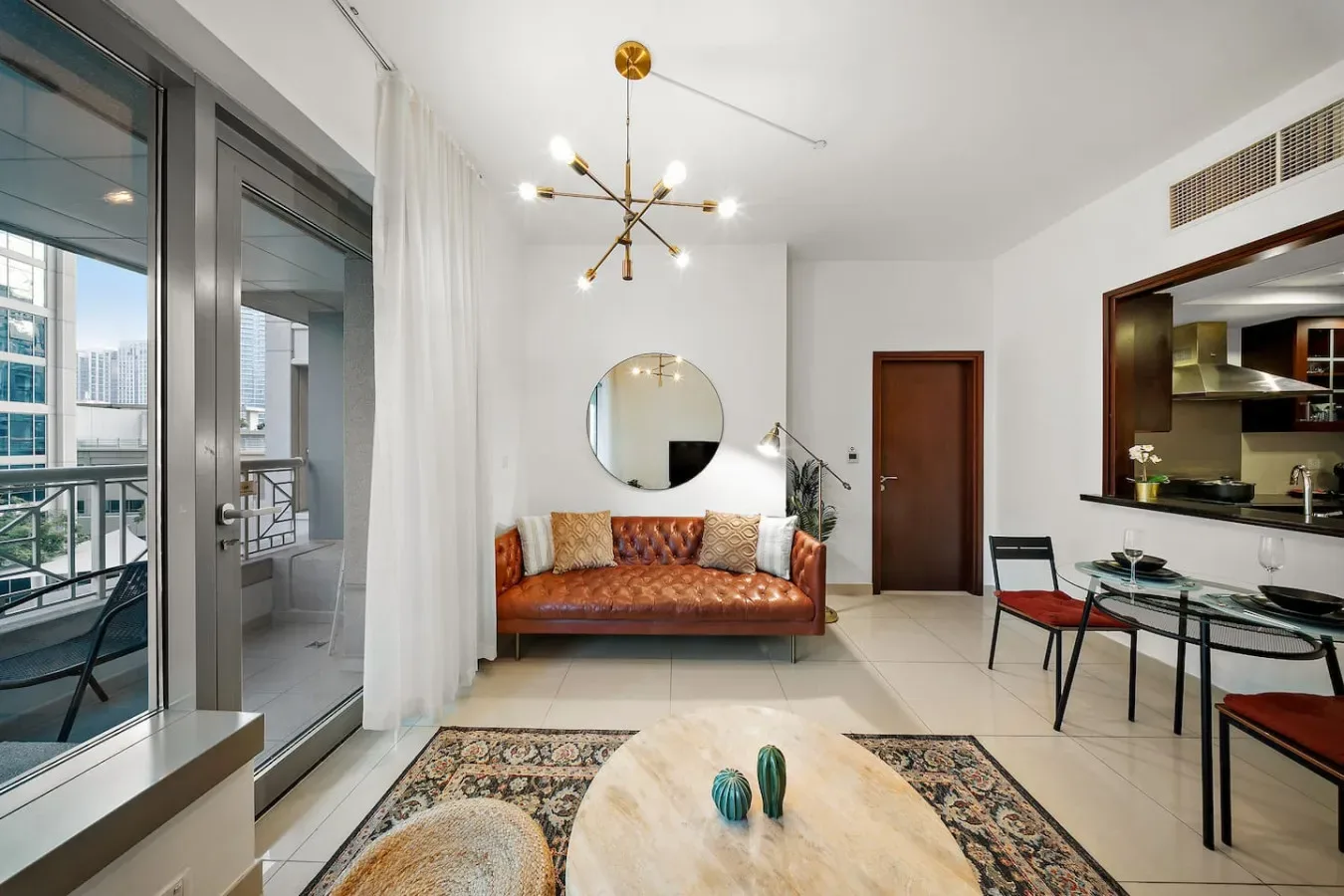 Una sala luminosa con un sofá de cuero y una mesa de comedor de vidrio.