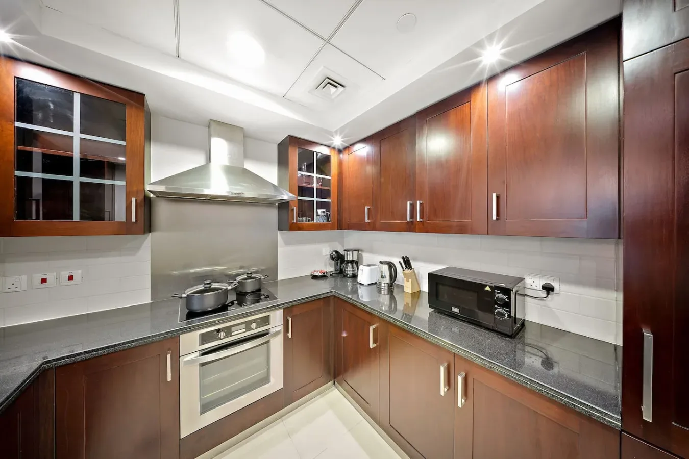 Una cocina moderna con gabinetes de madera oscura, una estufa y electrodomésticos sobre la encimera.