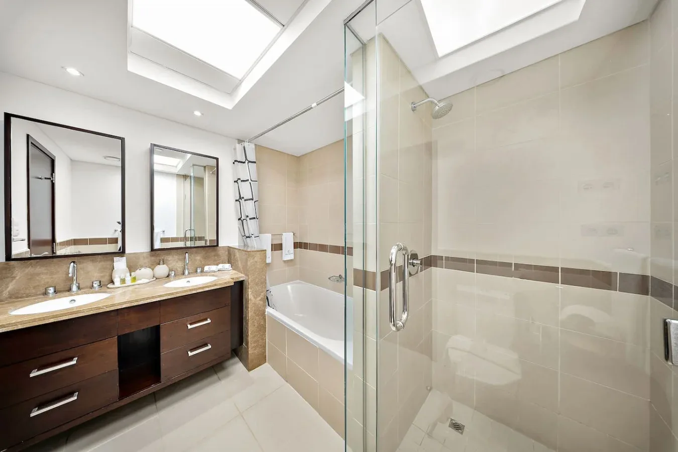 Un baño luminoso con un lavabo amplio, bañera y ducha de vidrio.