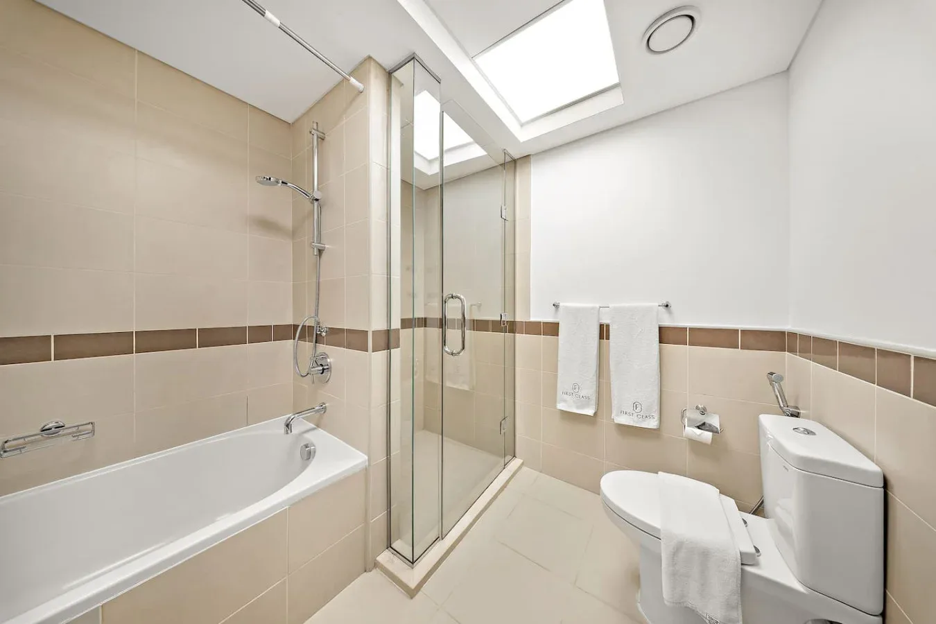 Un baño luminoso con bañera, ducha de vidrio y tragaluz.