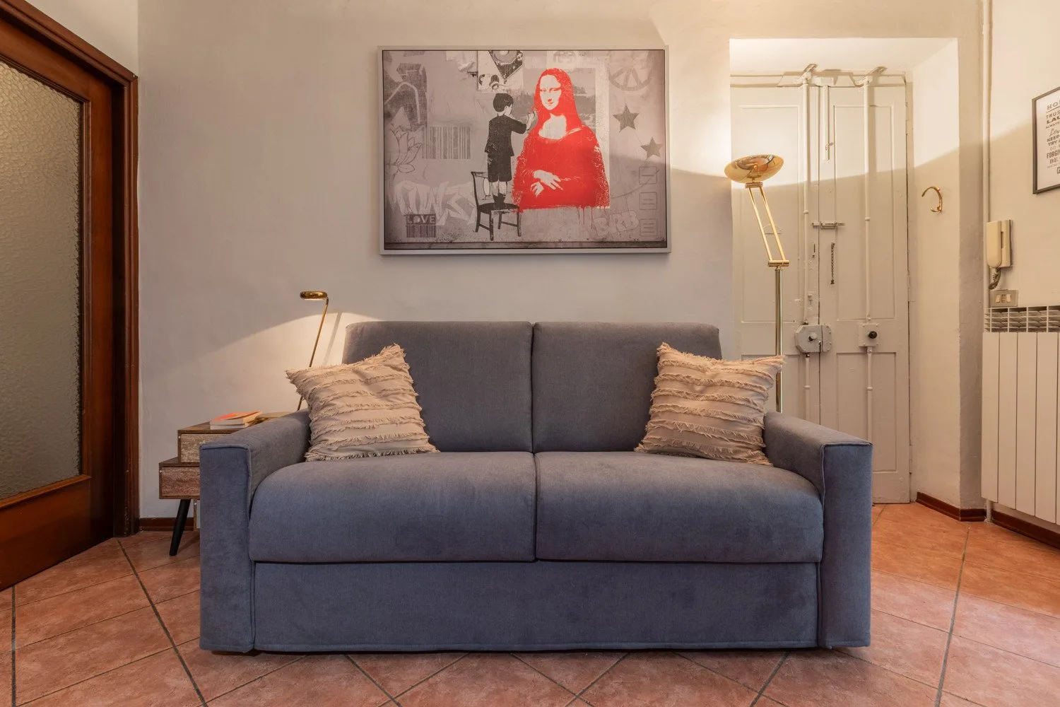 A living room with a gray sofa beneath a framed artwork.