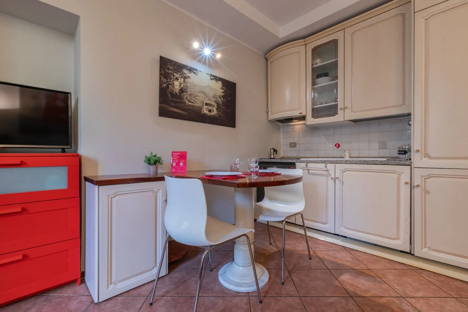 A compact kitchen and dining area with cream cabinets and a small table.