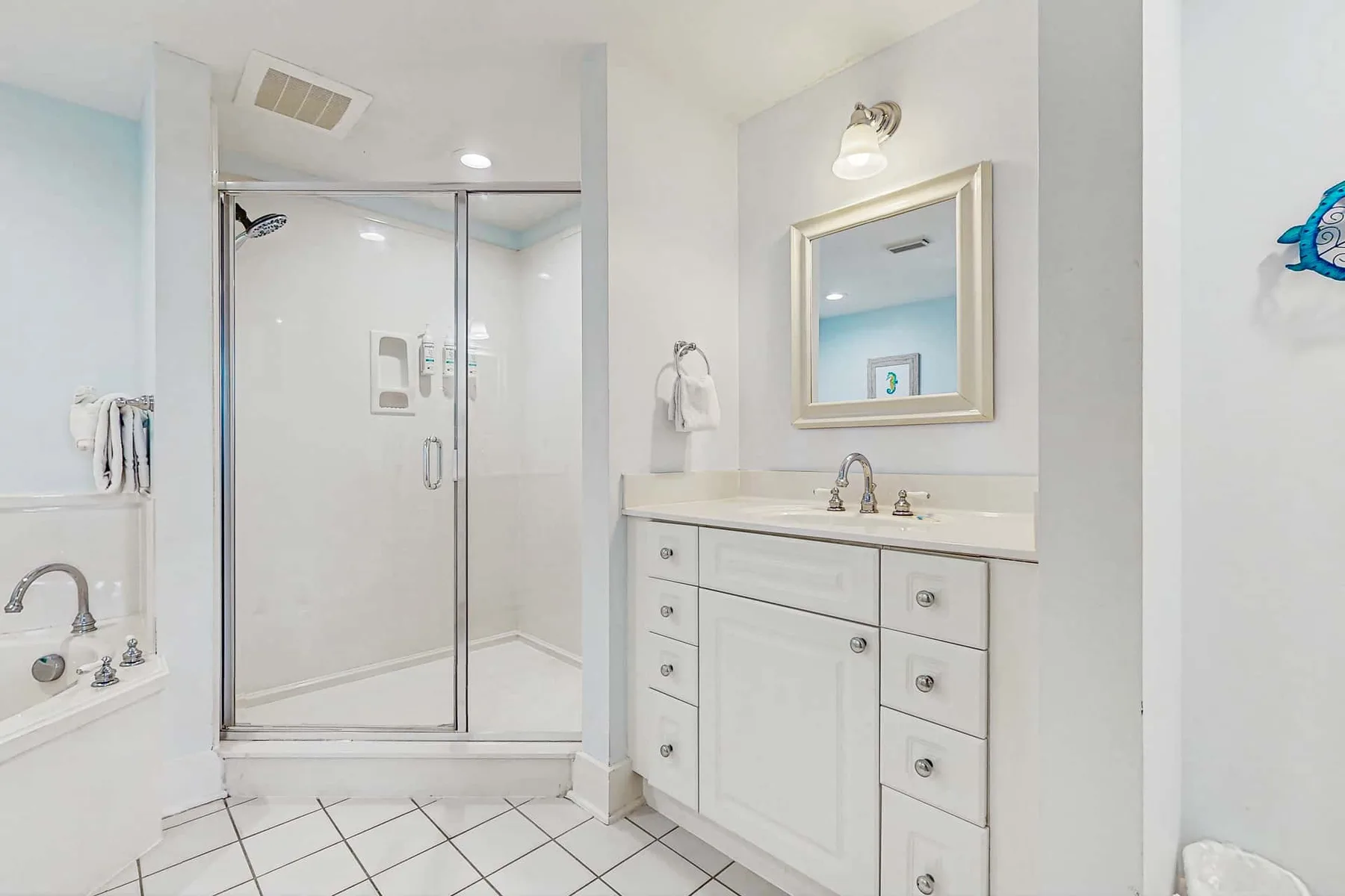 A bright bathroom with a glass shower and a white vanity.