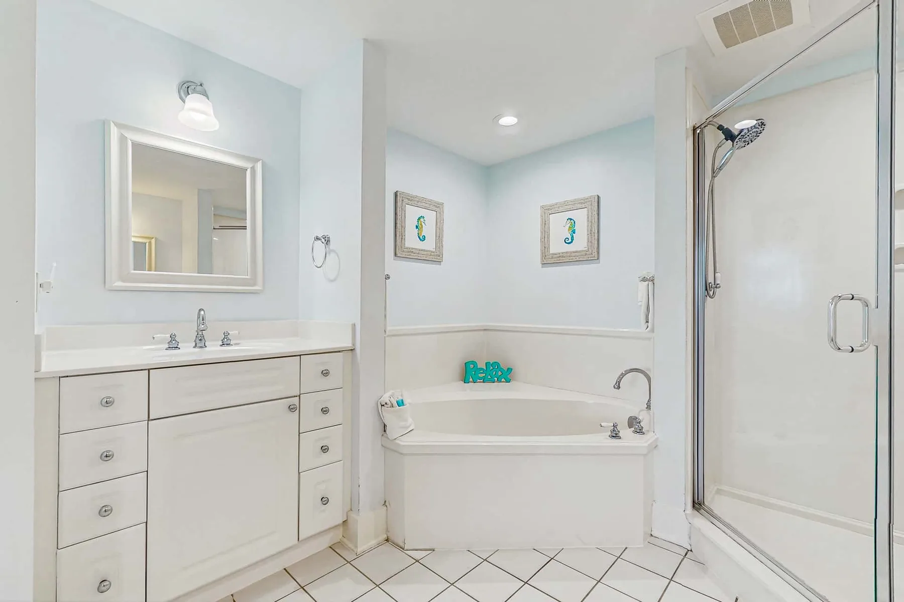 A bright bathroom with a vanity, bathtub, and glass shower.