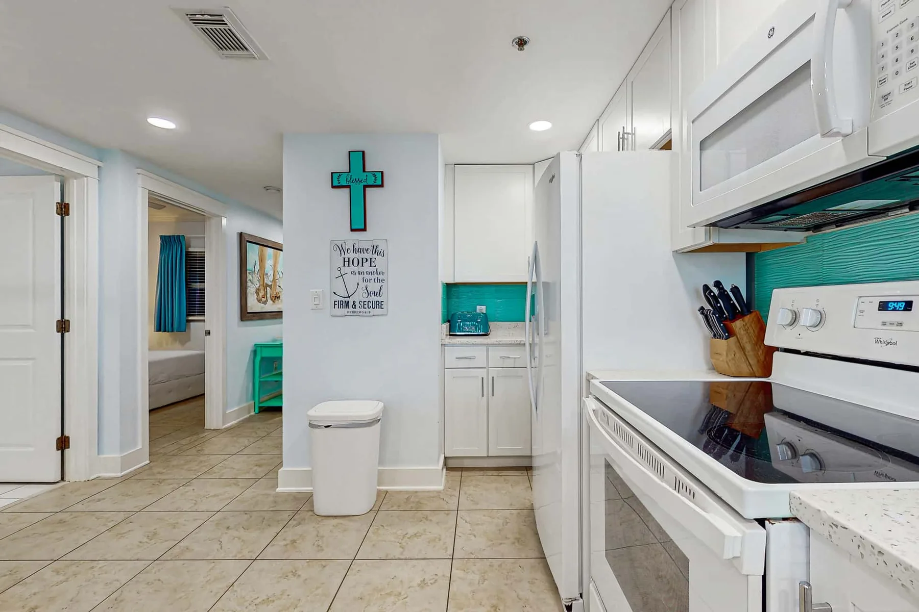 A bright kitchen with white cabinets, a stove, and a tiled floor.