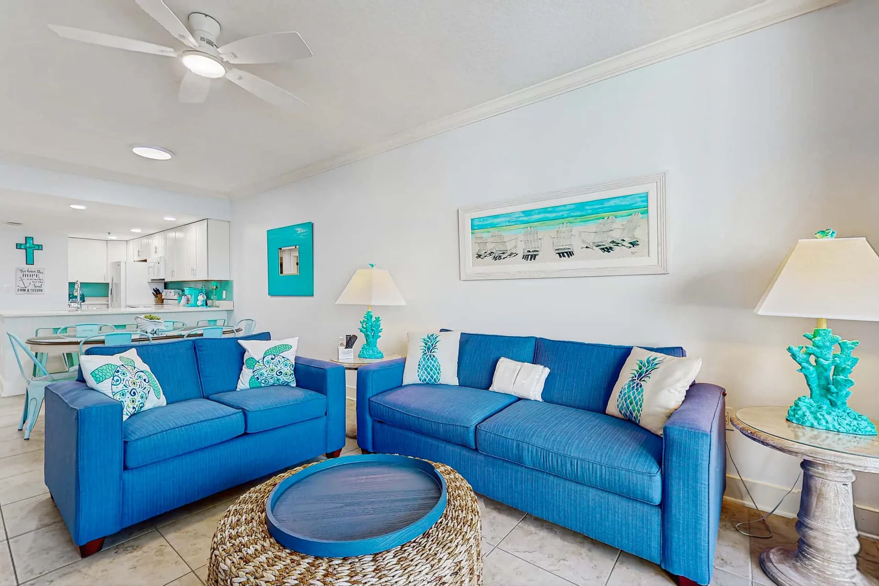 A bright living room with blue seating, a ceiling fan, and a framed picture.