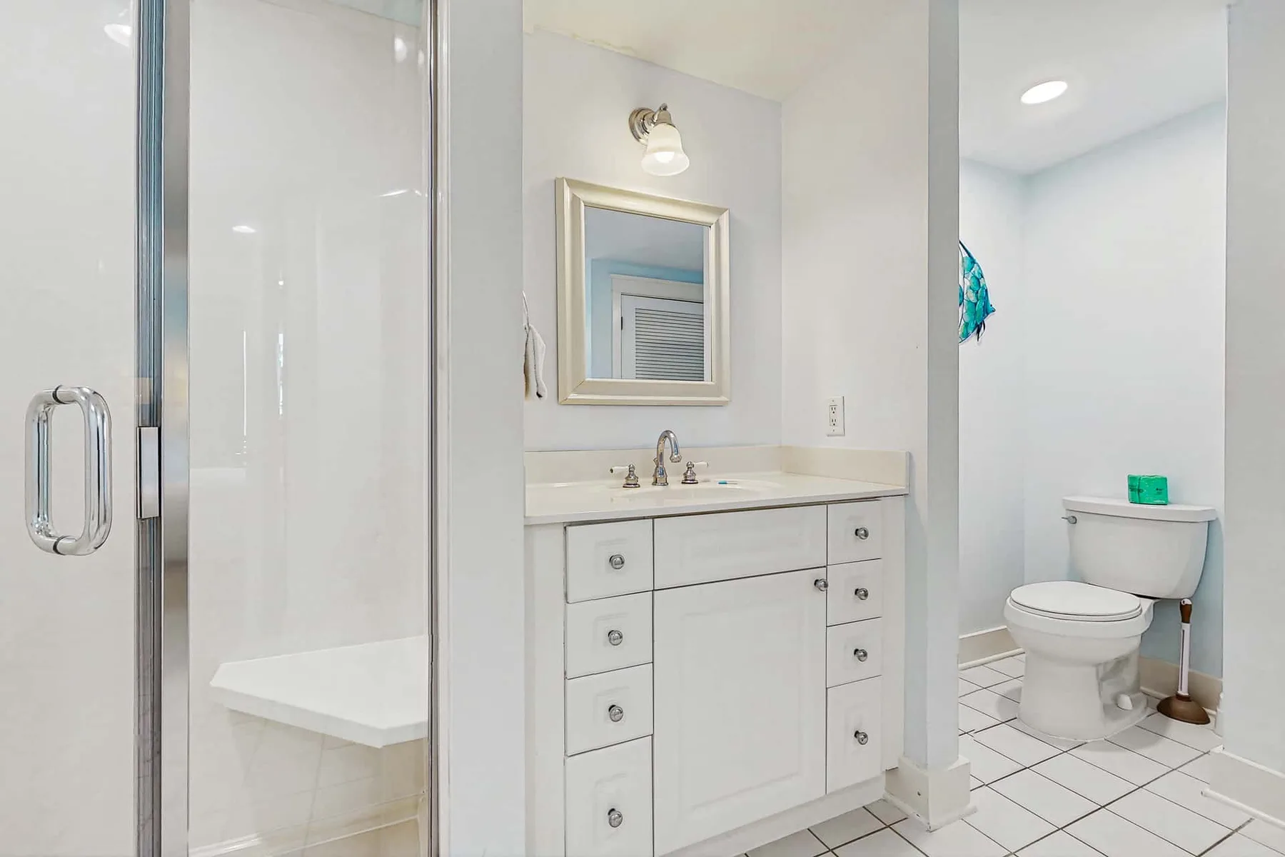 A bright bathroom with a vanity, mirror, shower, and toilet.