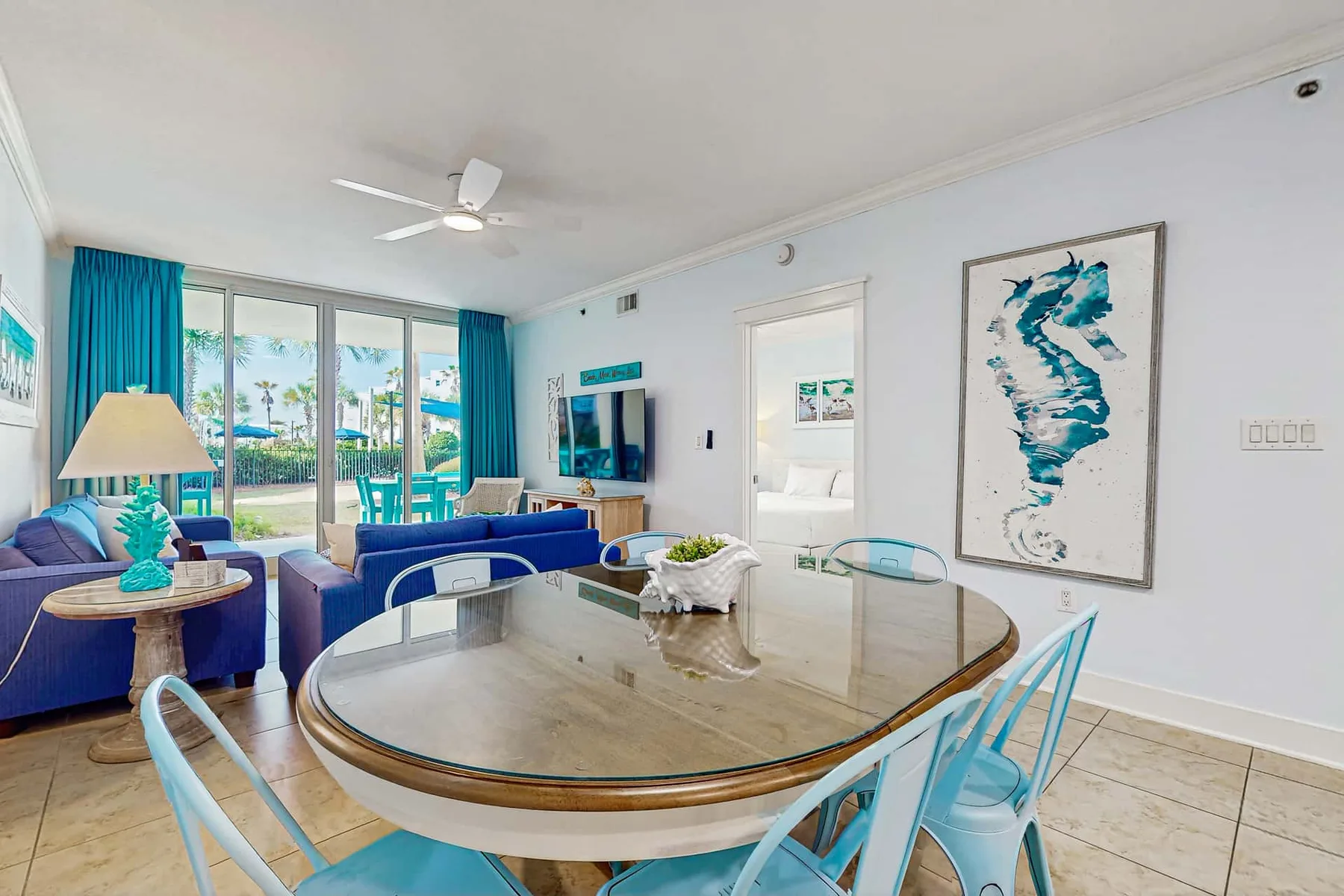 A bright dining area with an oval table beside large windows and blue curtains.