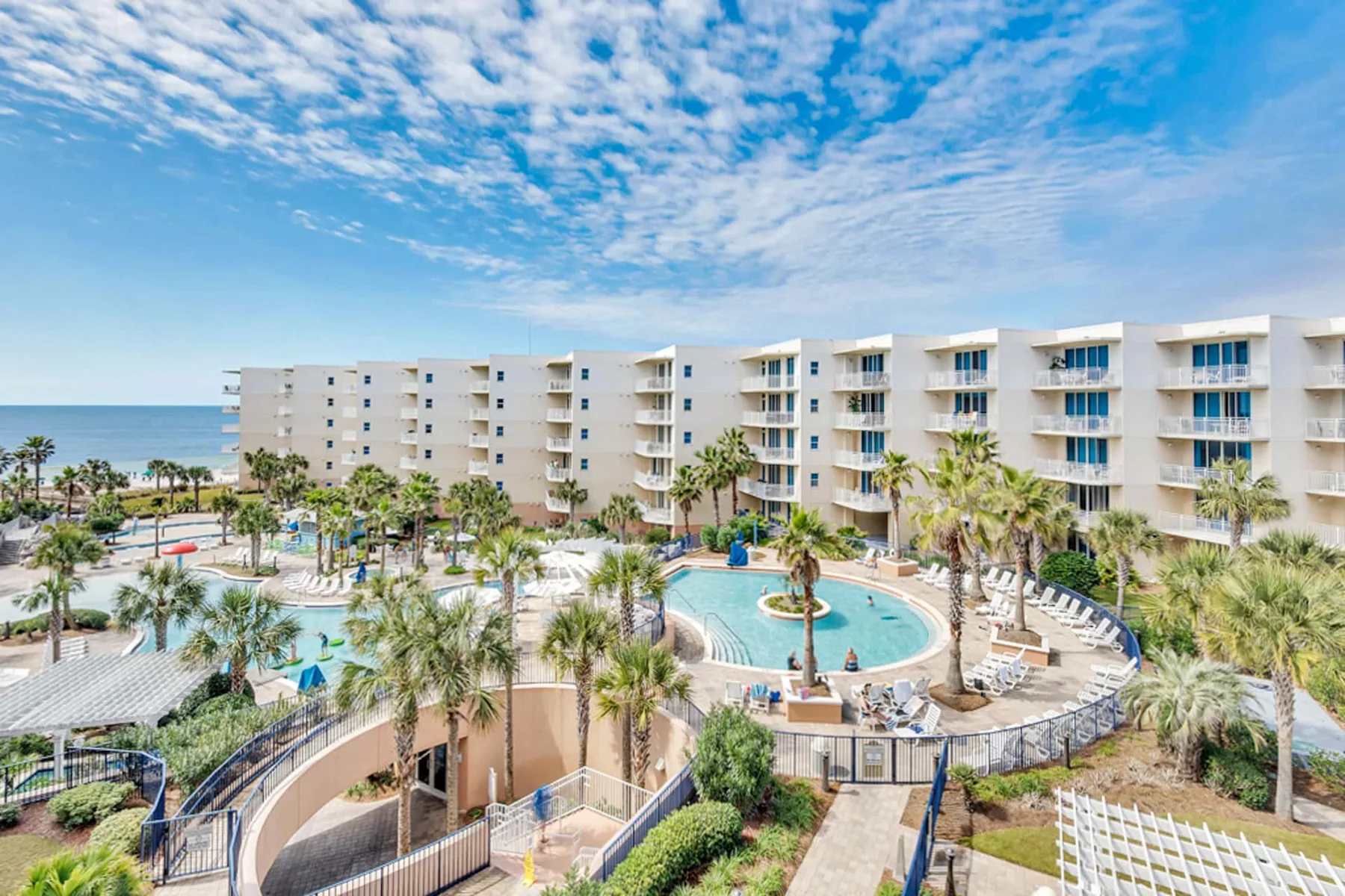 A resort courtyard with a curved swimming pool and palm trees.
