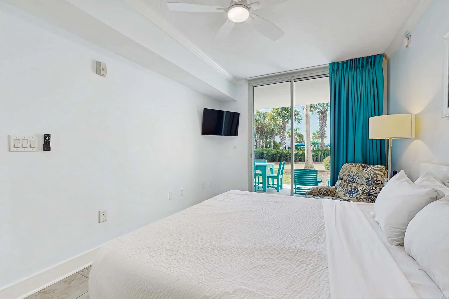 A bedroom with a neatly made bed and sliding glass doors opening to a patio.