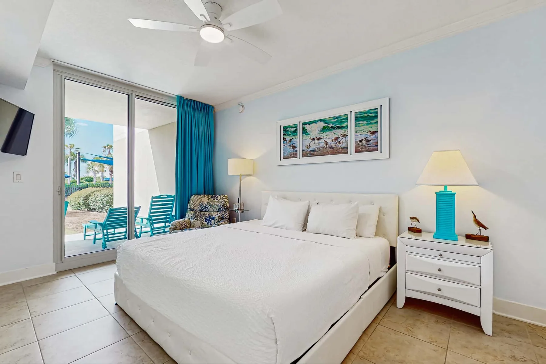 A bright bedroom with a large bed and sliding glass doors opening to a patio.
