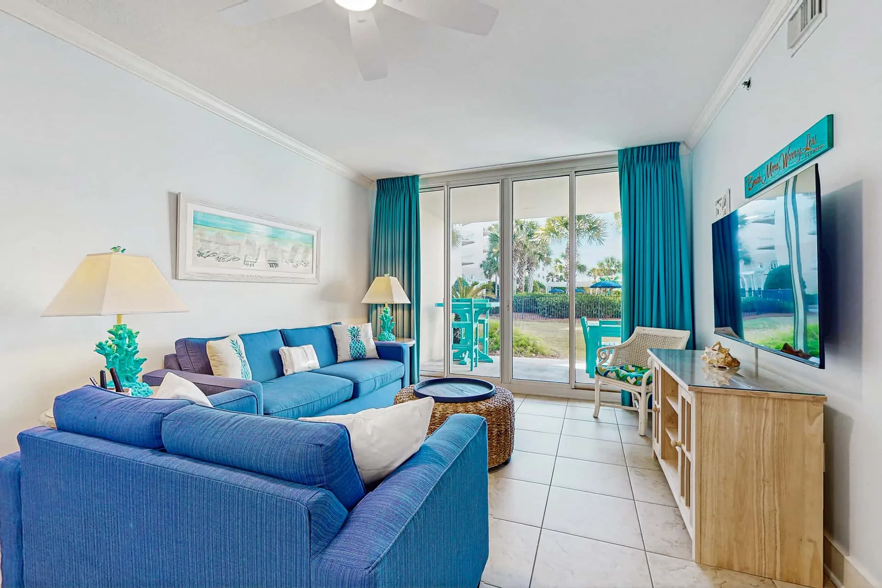 A living room with blue seating and sliding glass doors opening onto a patio.