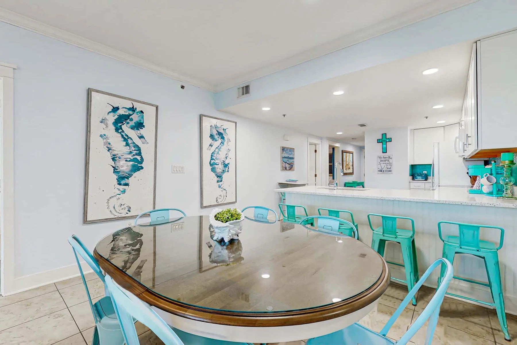 A bright dining area with a large oval table and turquoise seating.