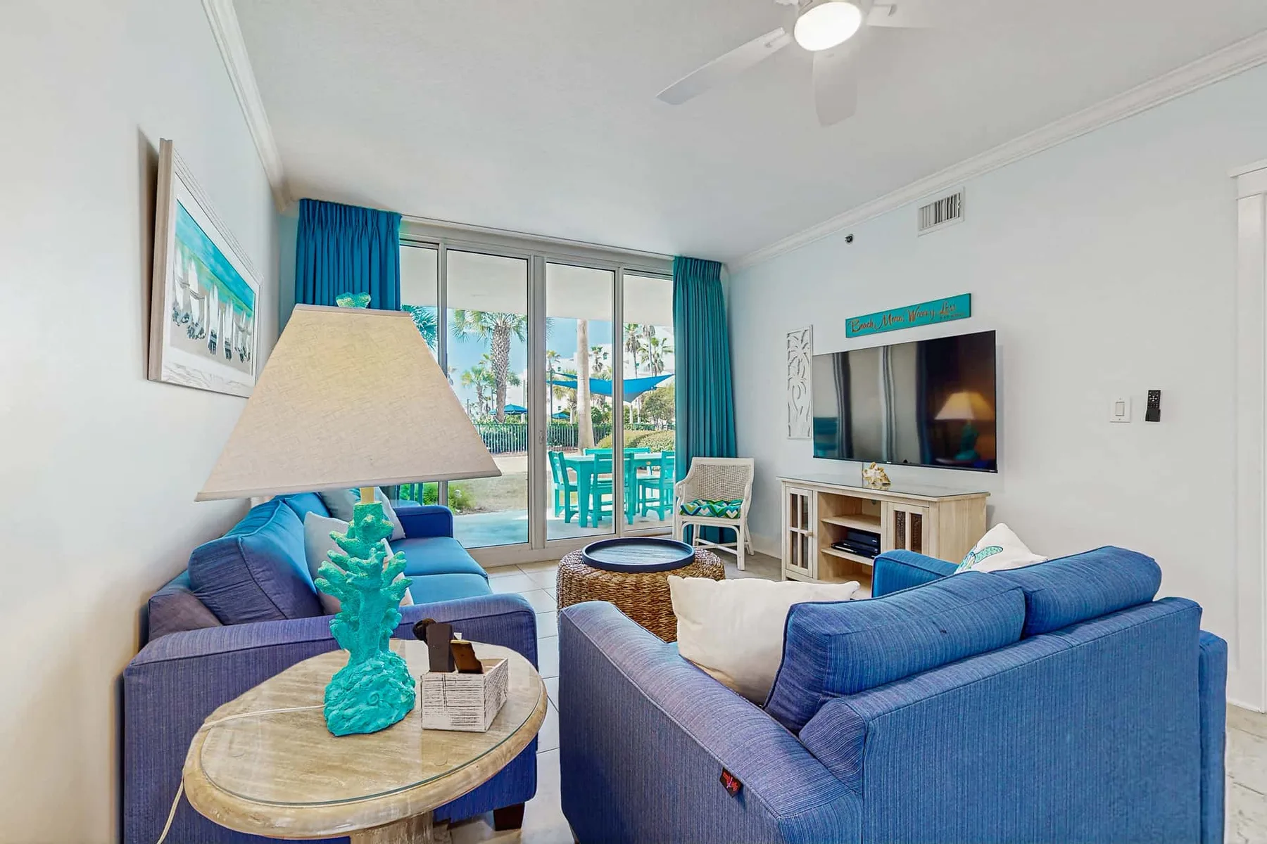 A bright living room with blue seating and glass doors opening onto a patio.