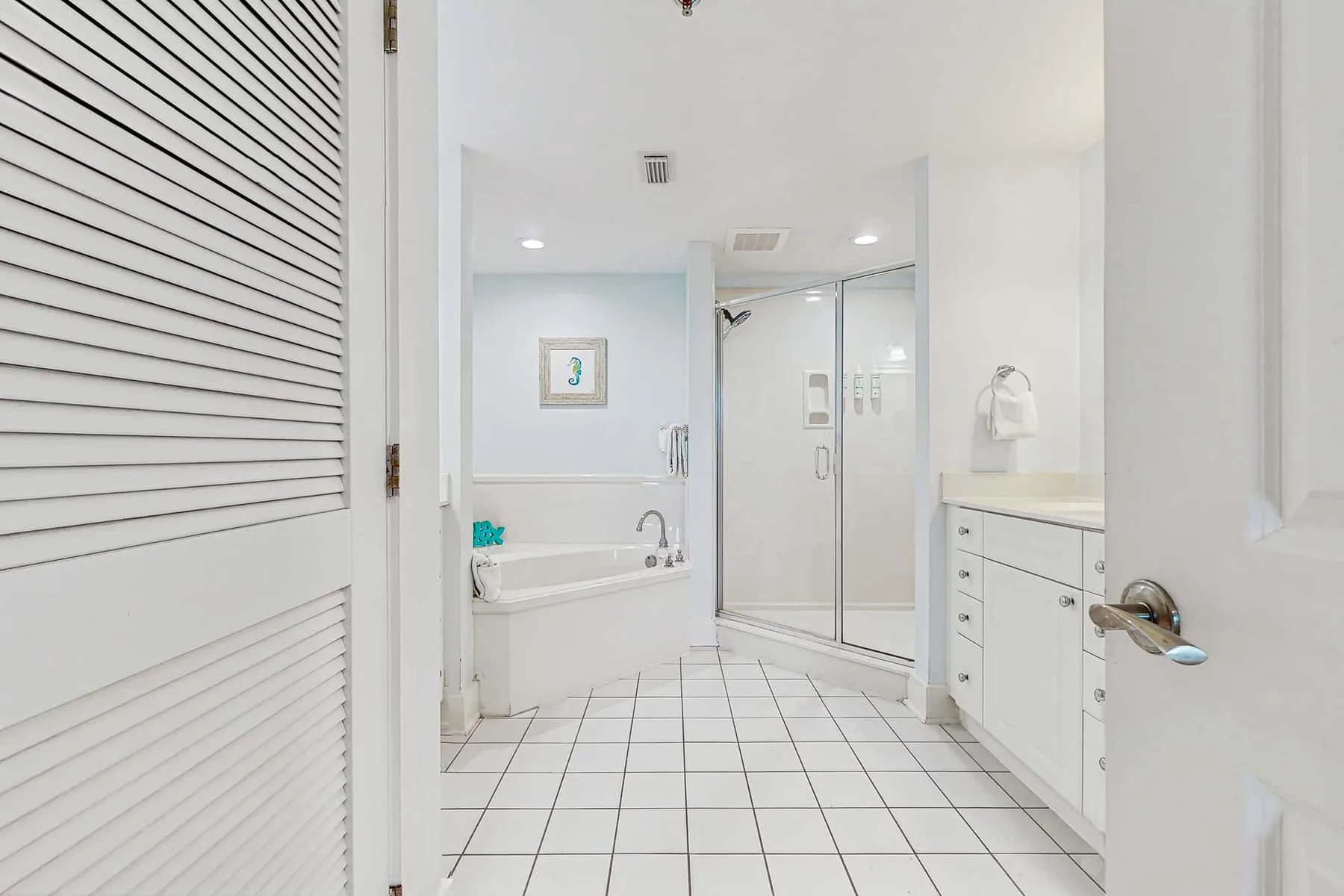 A bright bathroom with a bathtub, glass shower, and white vanity.