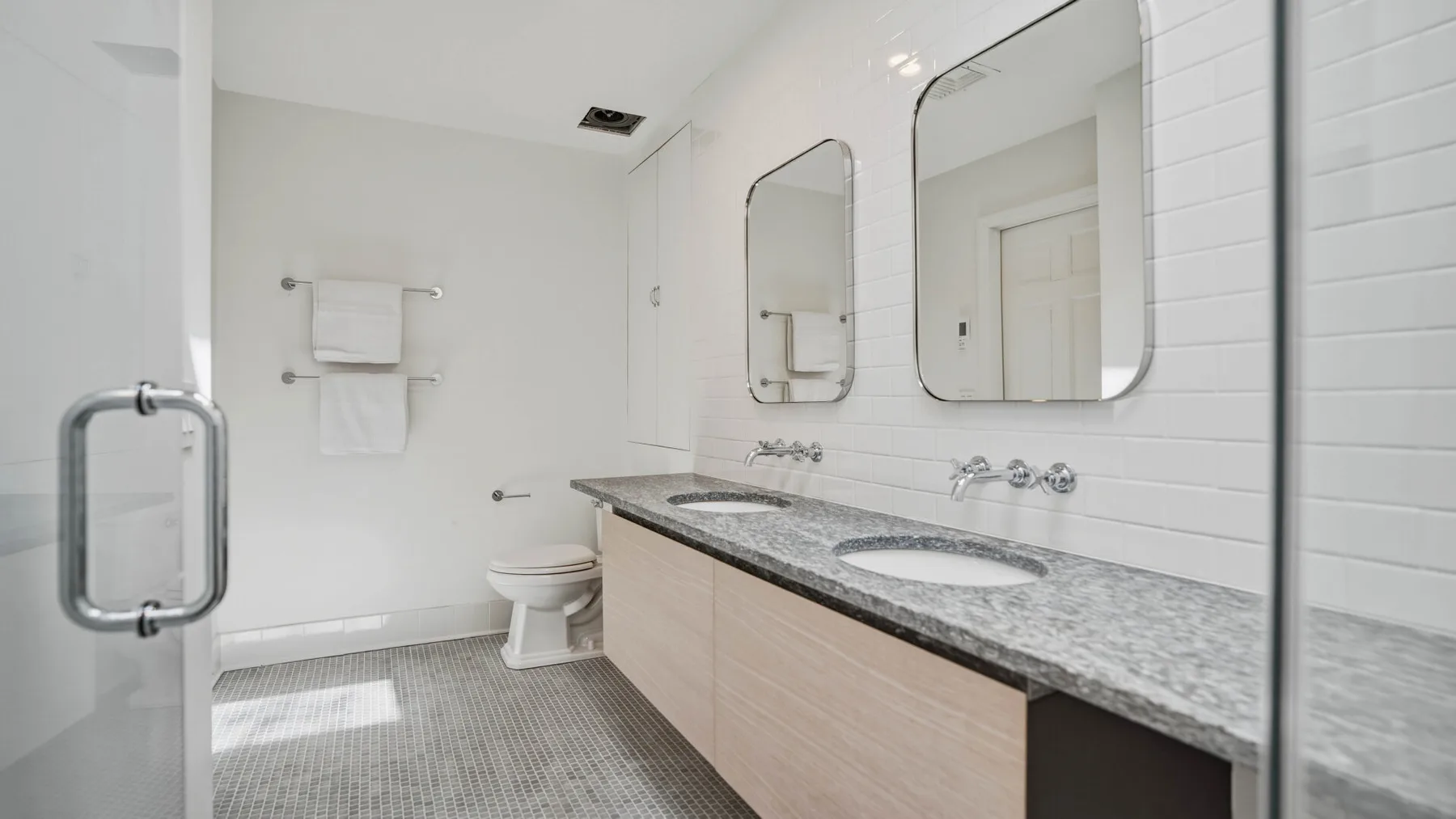 Un baño luminoso con un tocador largo, dos lavabos y espejos de pared.