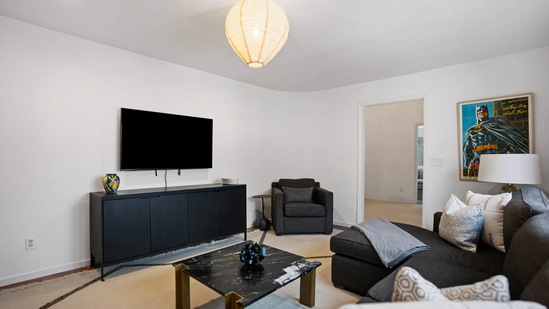 Una sala de estar con un televisor, asientos y una mesa de centro.