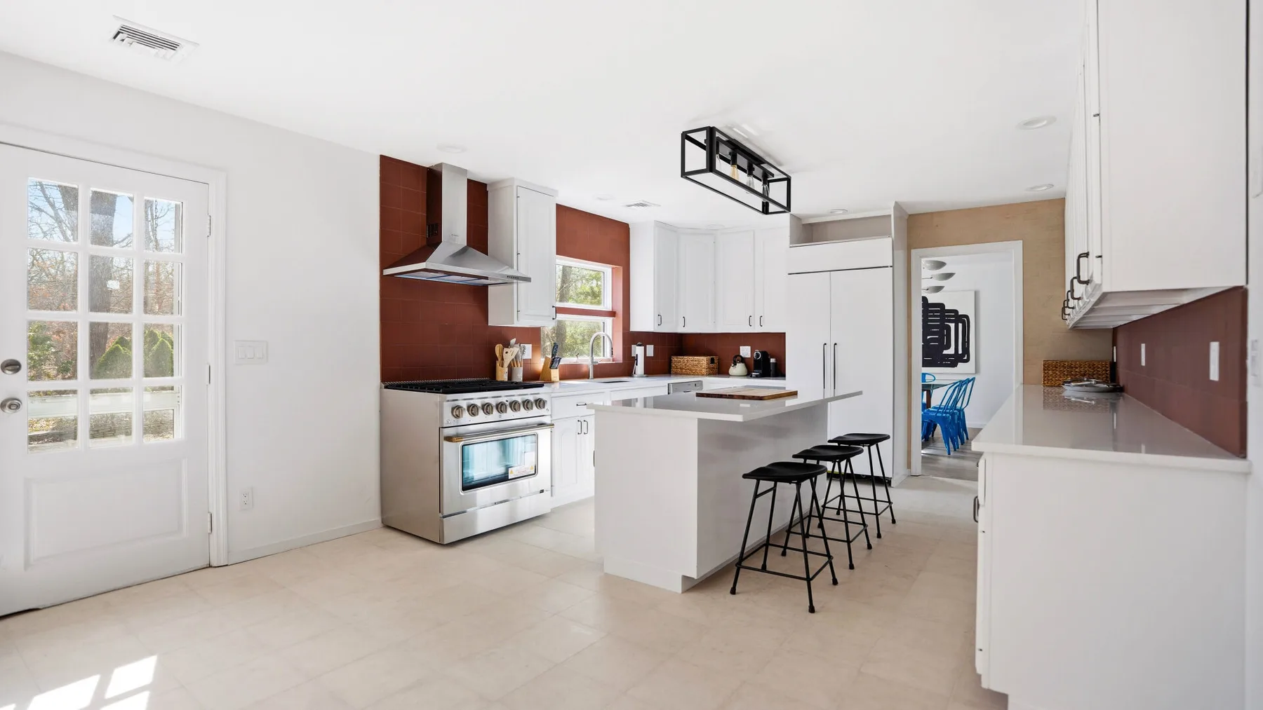 Una cocina luminosa con una isla central y taburetes.