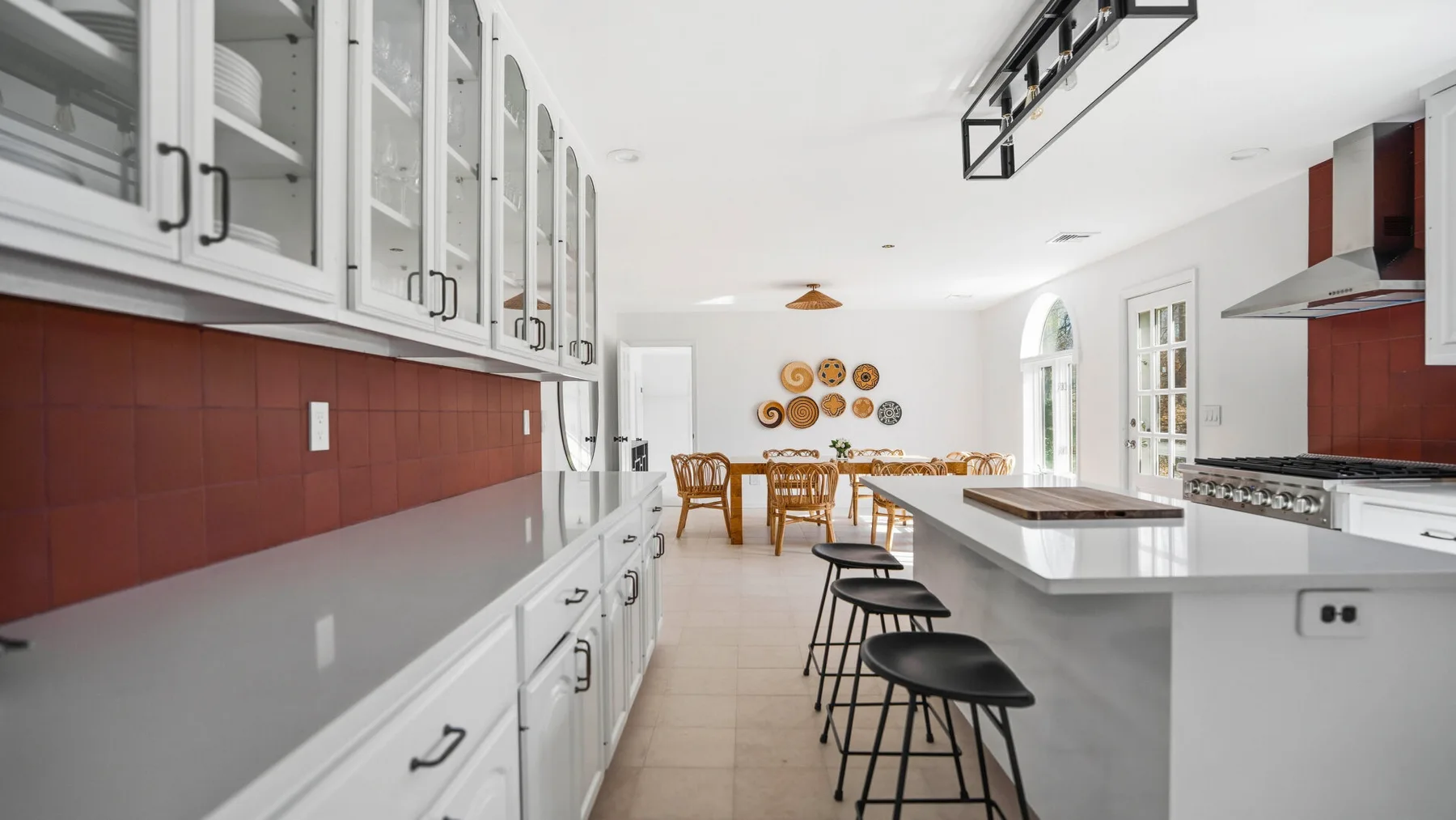 Una cocina luminosa con encimeras largas y una fila de taburetes.