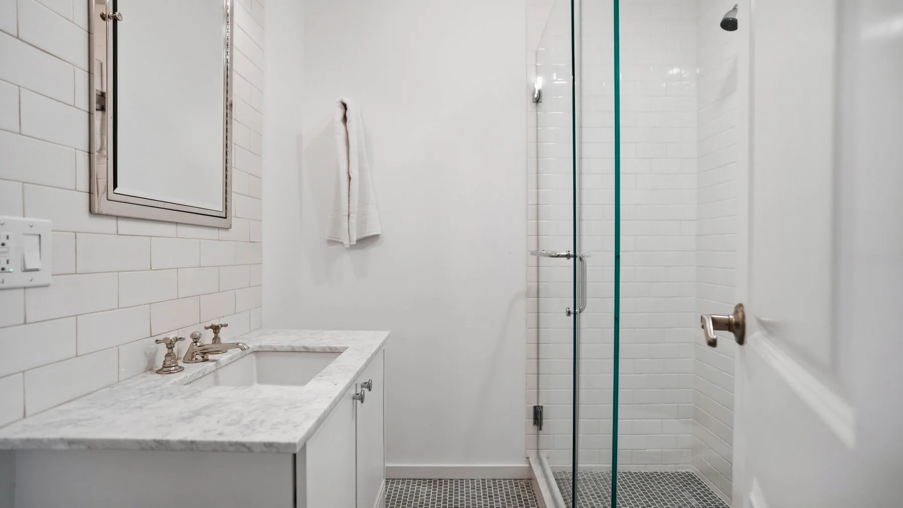 Un baño luminoso con un lavabo blanco y una ducha de vidrio.