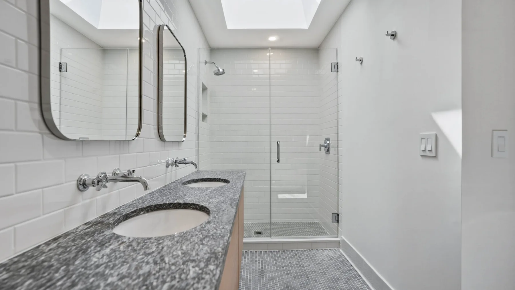 Un baño luminoso con un tocador largo y una ducha de vidrio.