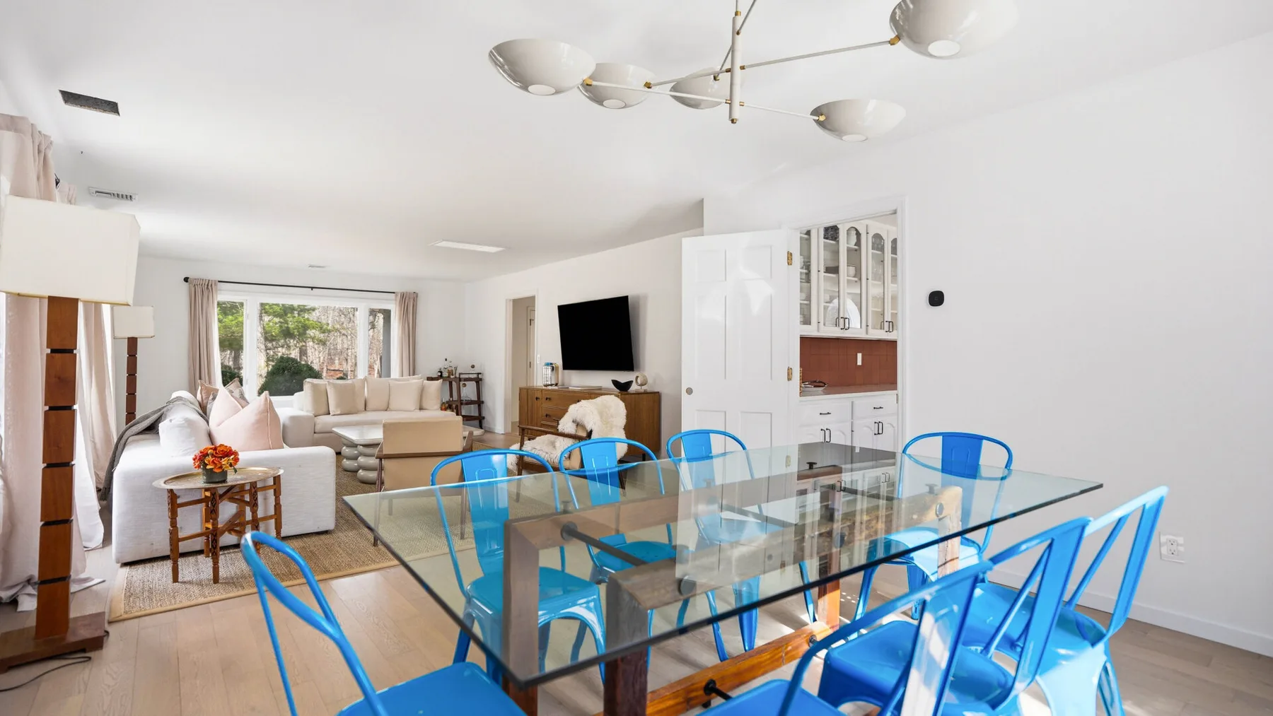 Una luminosa sala de estar y comedor con una mesa de vidrio y asientos azules.