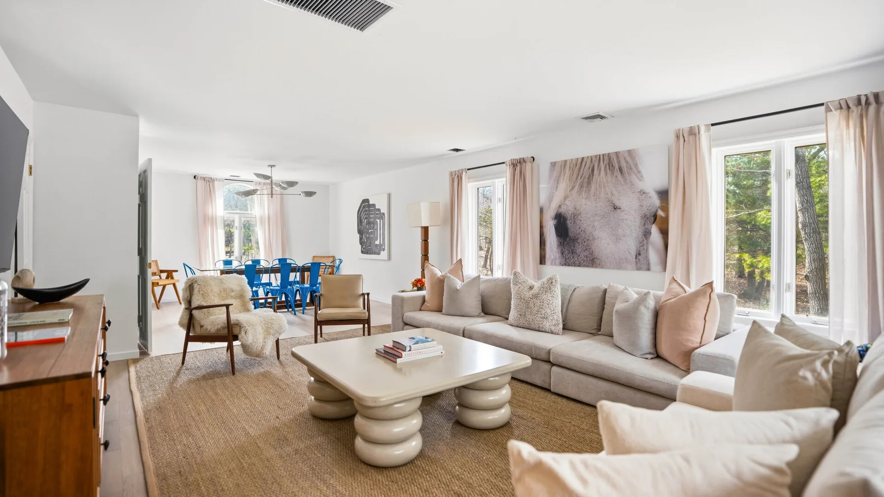Una sala luminosa con asientos neutros y un comedor junto a las ventanas.