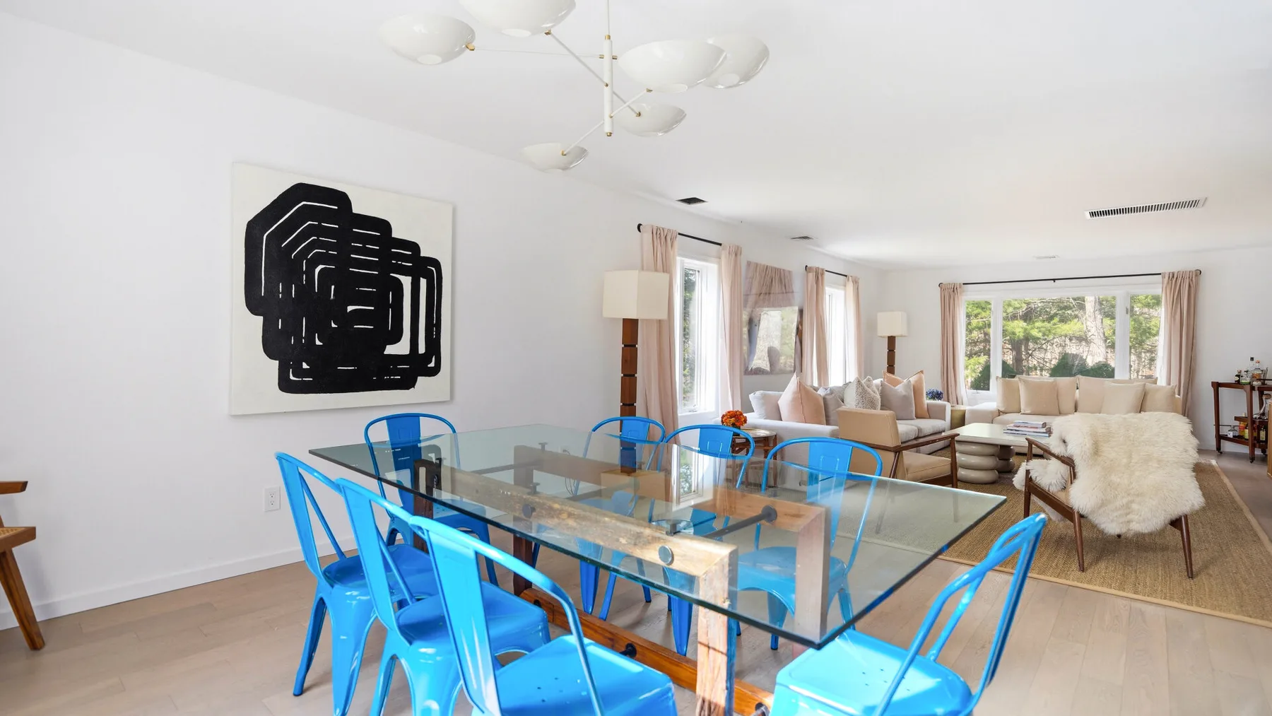 Un luminoso comedor y sala de estar con una mesa de vidrio y asientos azules.