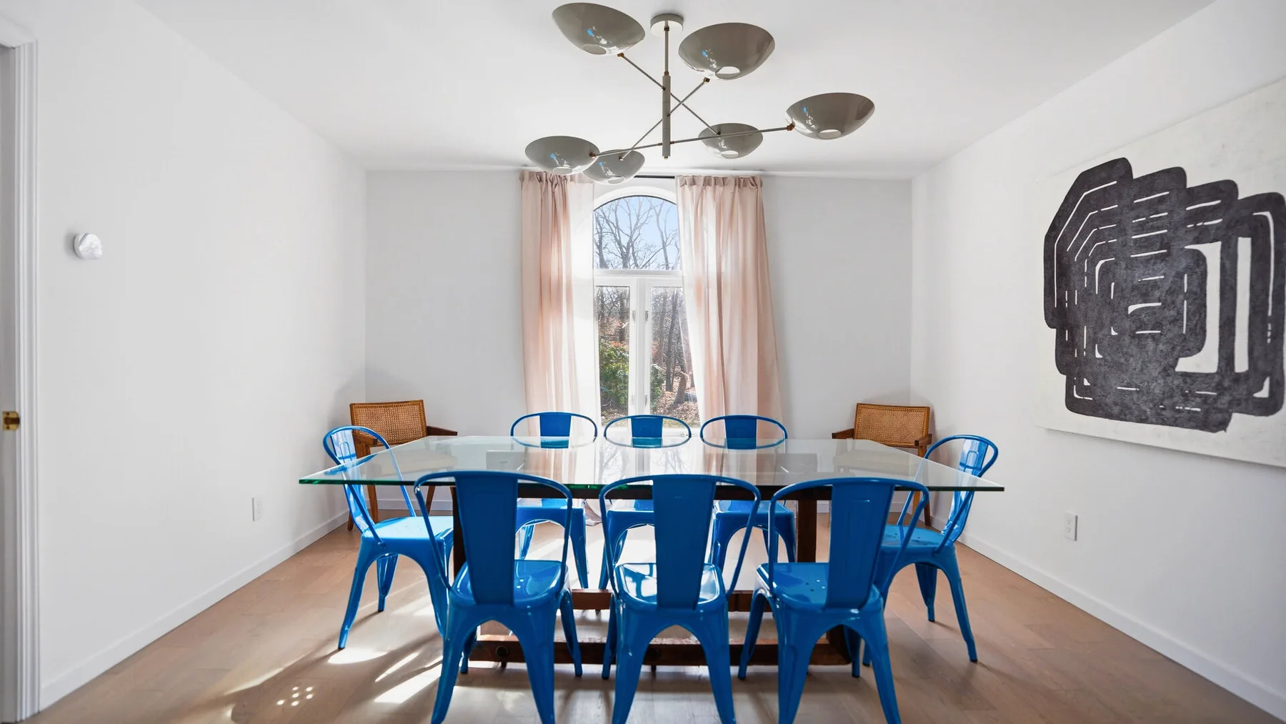Un comedor con asientos azules alrededor de una mesa bajo una lámpara colgante.