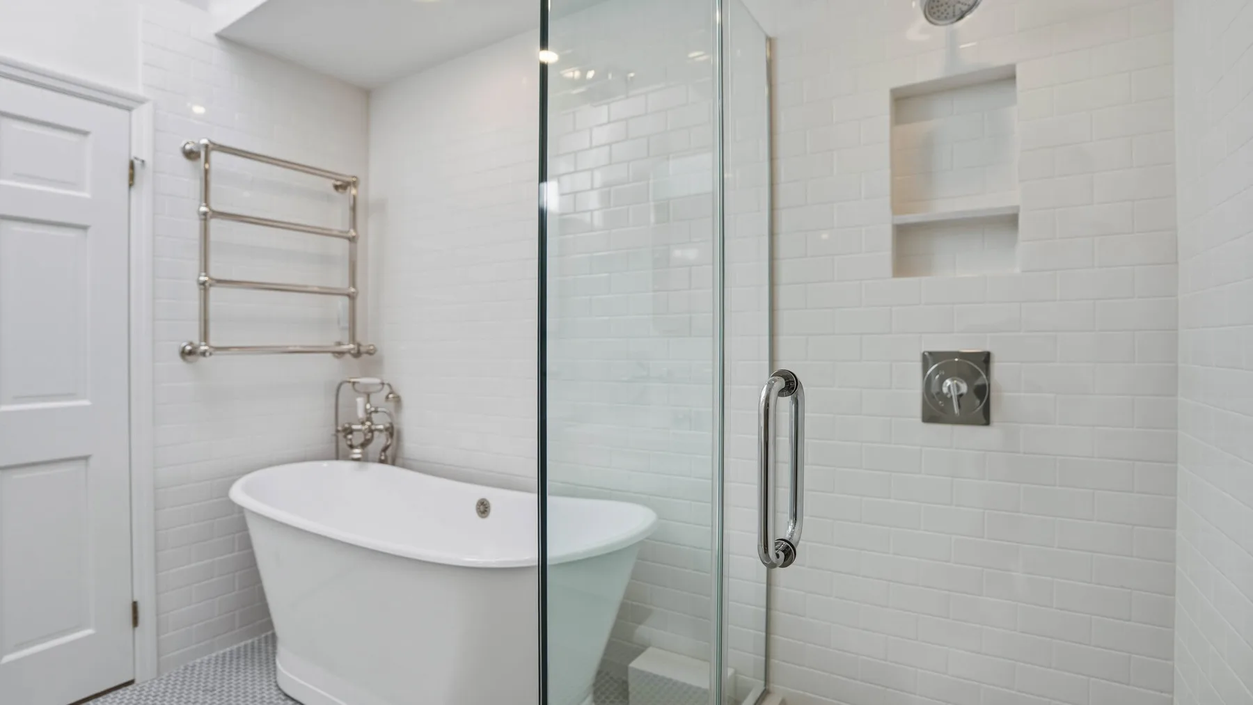 Un baño luminoso con azulejos, bañera y panel de ducha de vidrio.