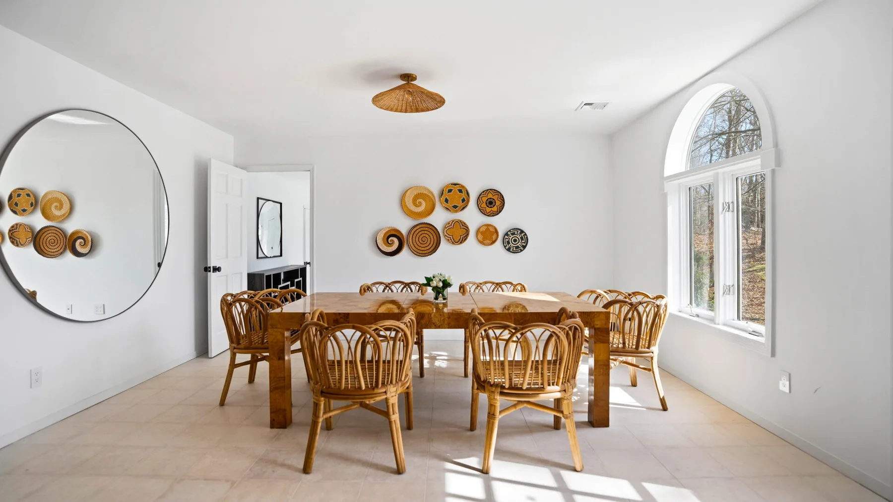 Un comedor luminoso con una mesa larga de madera y sillas tejidas.