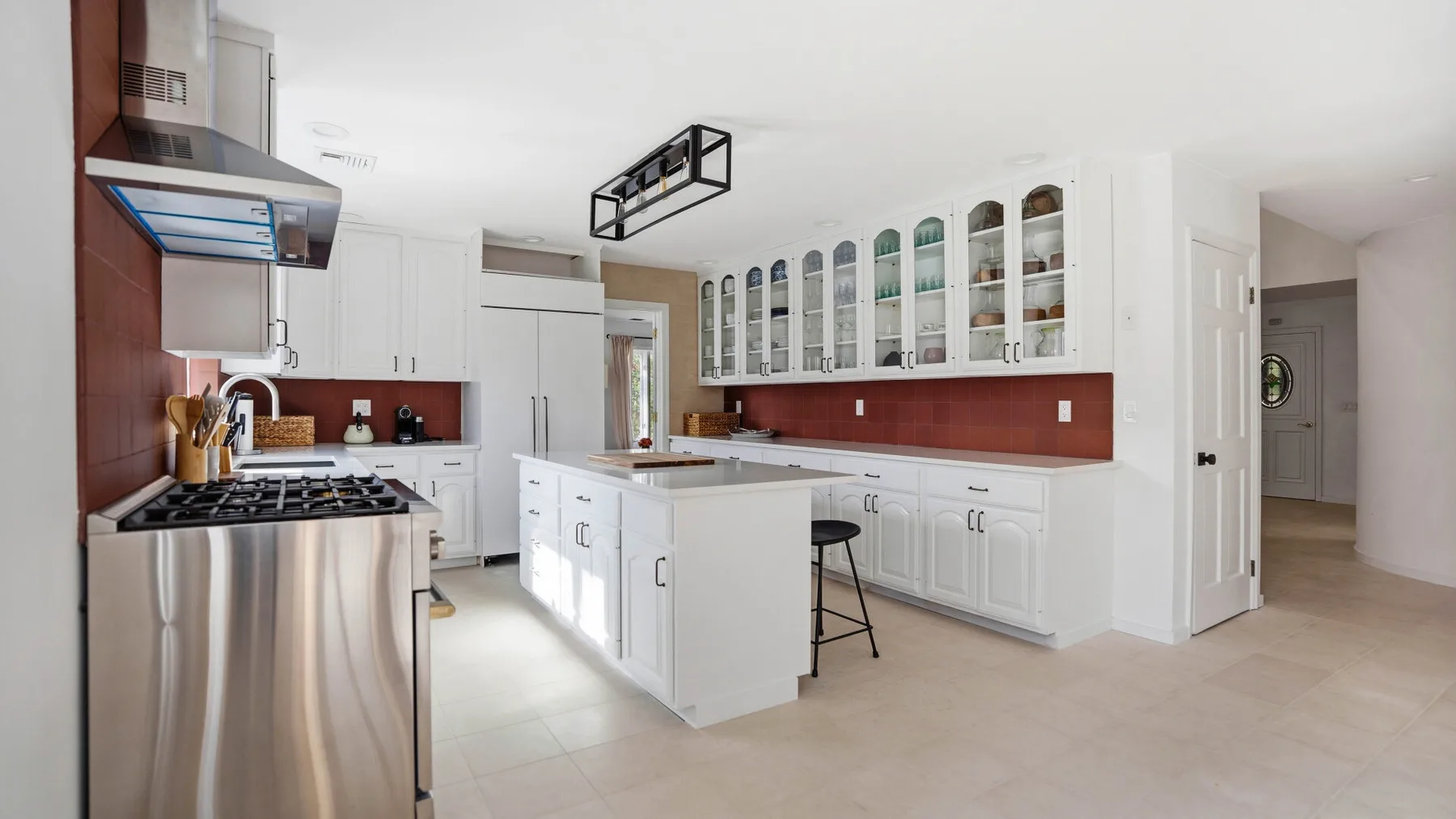 Una cocina luminosa con gabinetes blancos, una isla central y electrodomésticos de acero inoxidable.