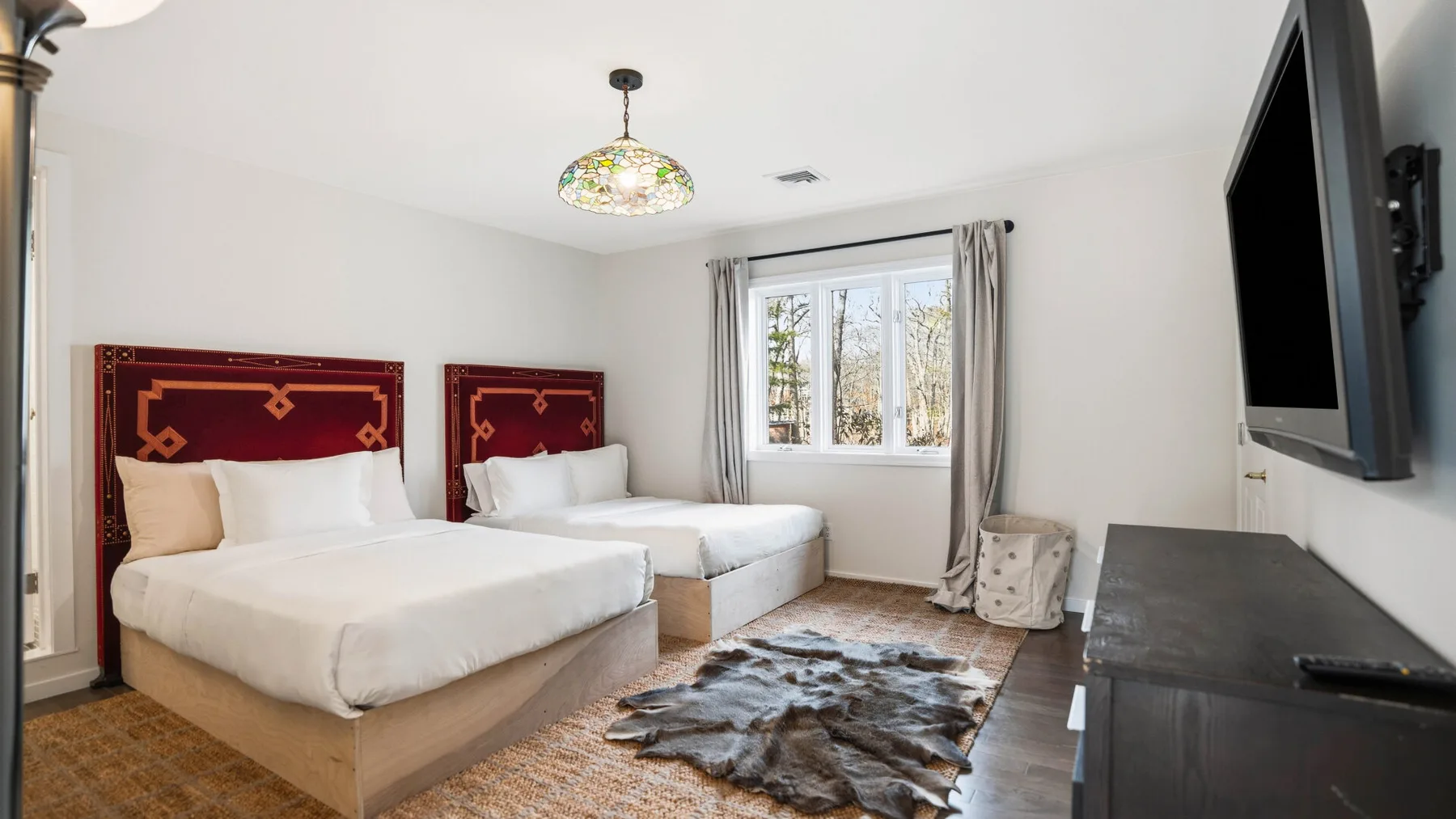 Un dormitorio con dos camas, una ventana y una alfombra estampada.