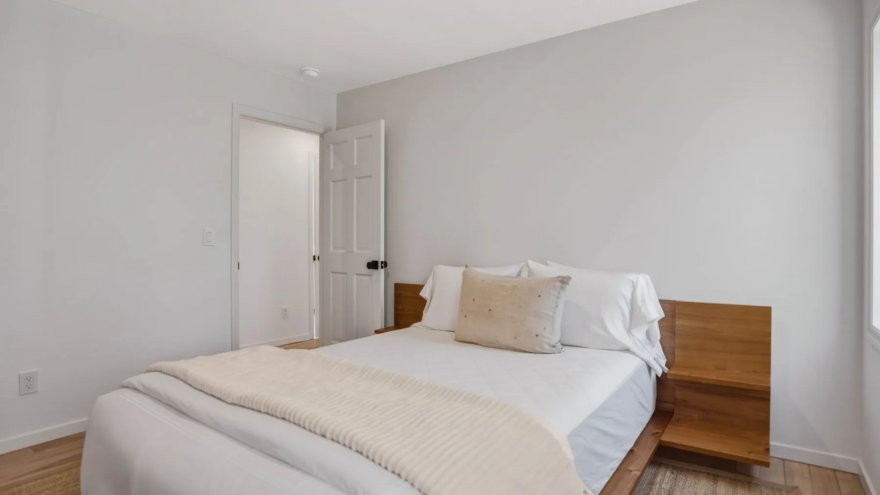 Un dormitorio con una cama, ropa de cama clara y un cabecero de madera.