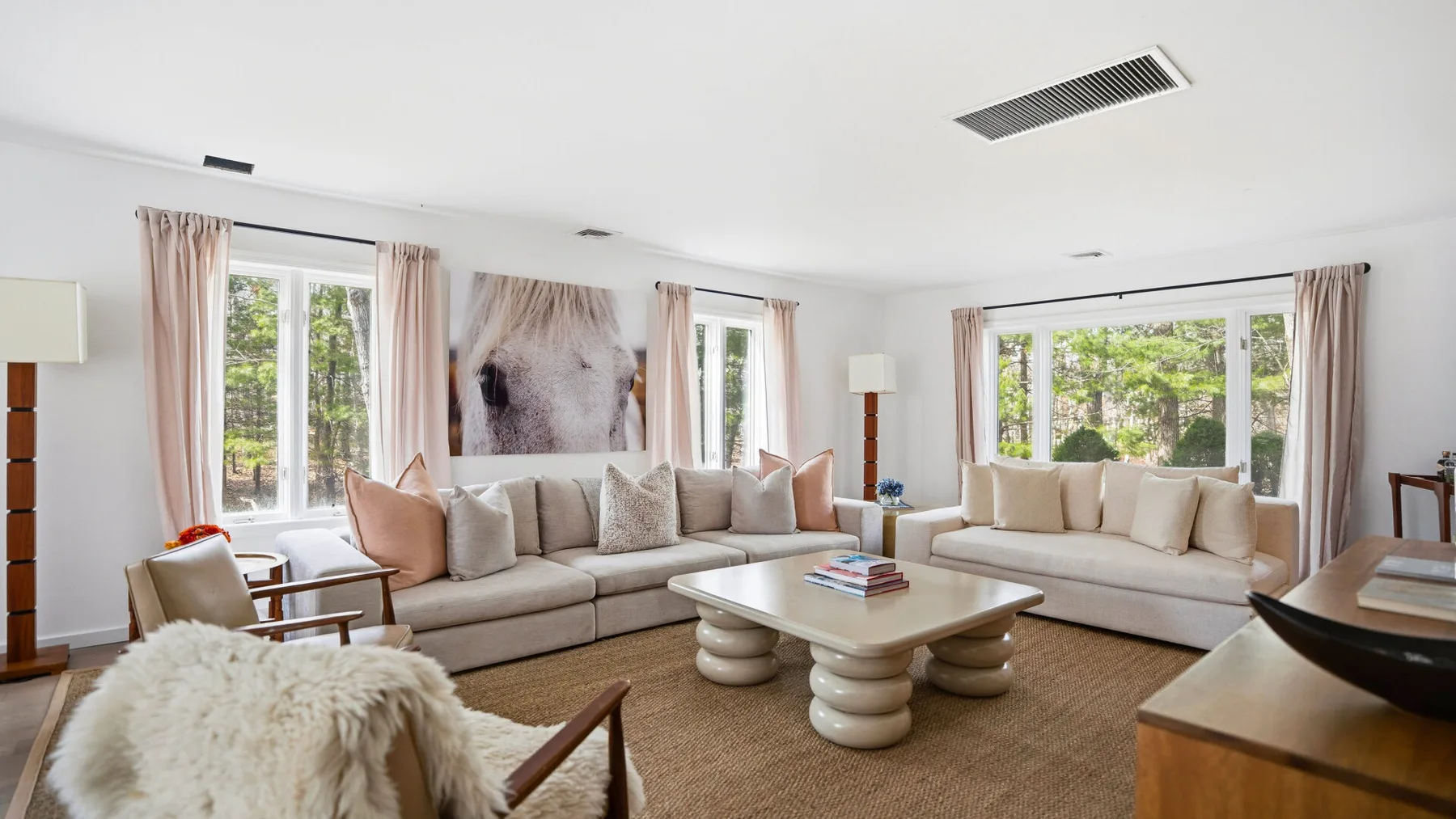 Una sala de estar luminosa con asientos acolchados, ventanas grandes y una mesa de centro baja.