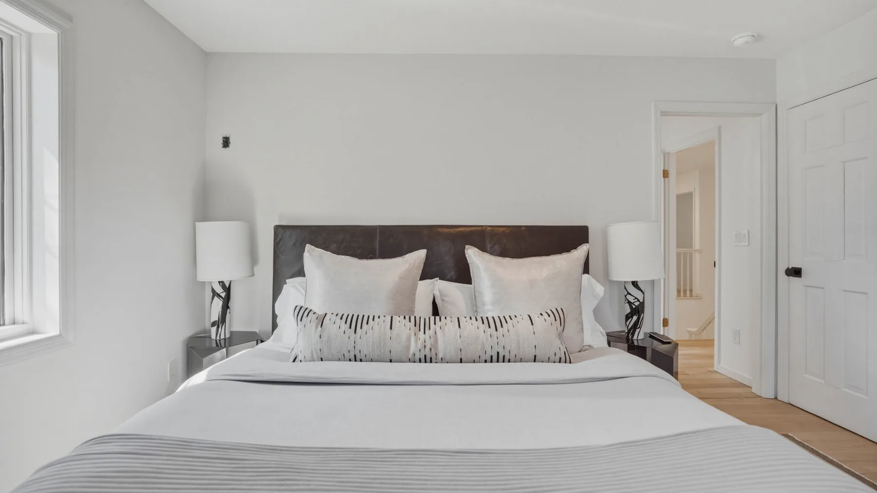 Un dormitorio luminoso con una cama bien tendida y una puerta abierta.